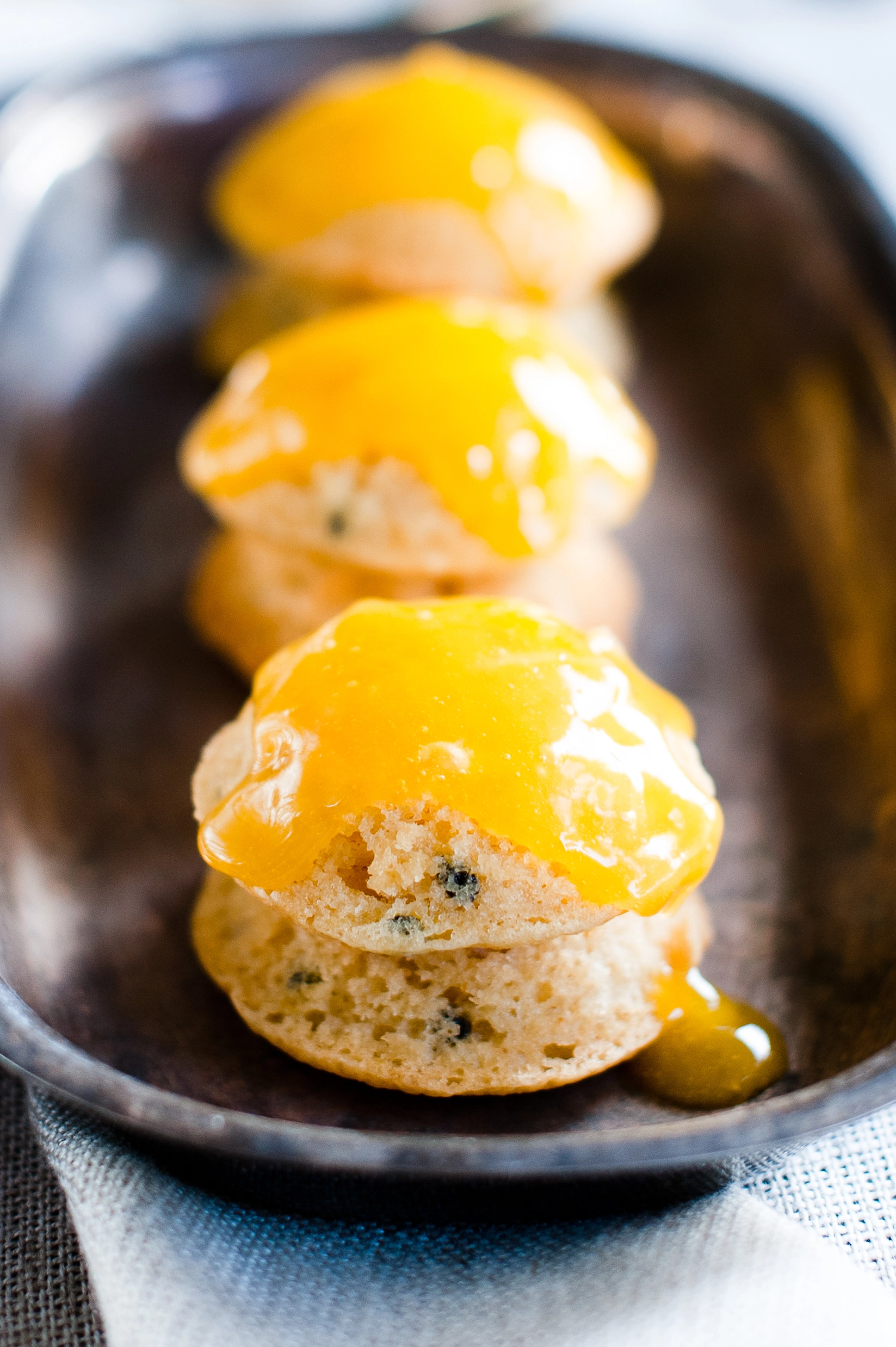 Small gluten free passionfruit cakes topped with smooth lime curd icing, showing a light, fluffy crumb and fresh passionfruit seeds; a bright and zesty mini cake dessert.