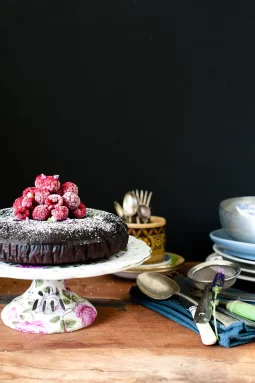 A dense, moist gluten free and dairy free chocolate mud cake made with kombucha, sliced to show its rich fudgy crumb; dark chocolate cake topped simply and perfect for allergy-friendly baking.