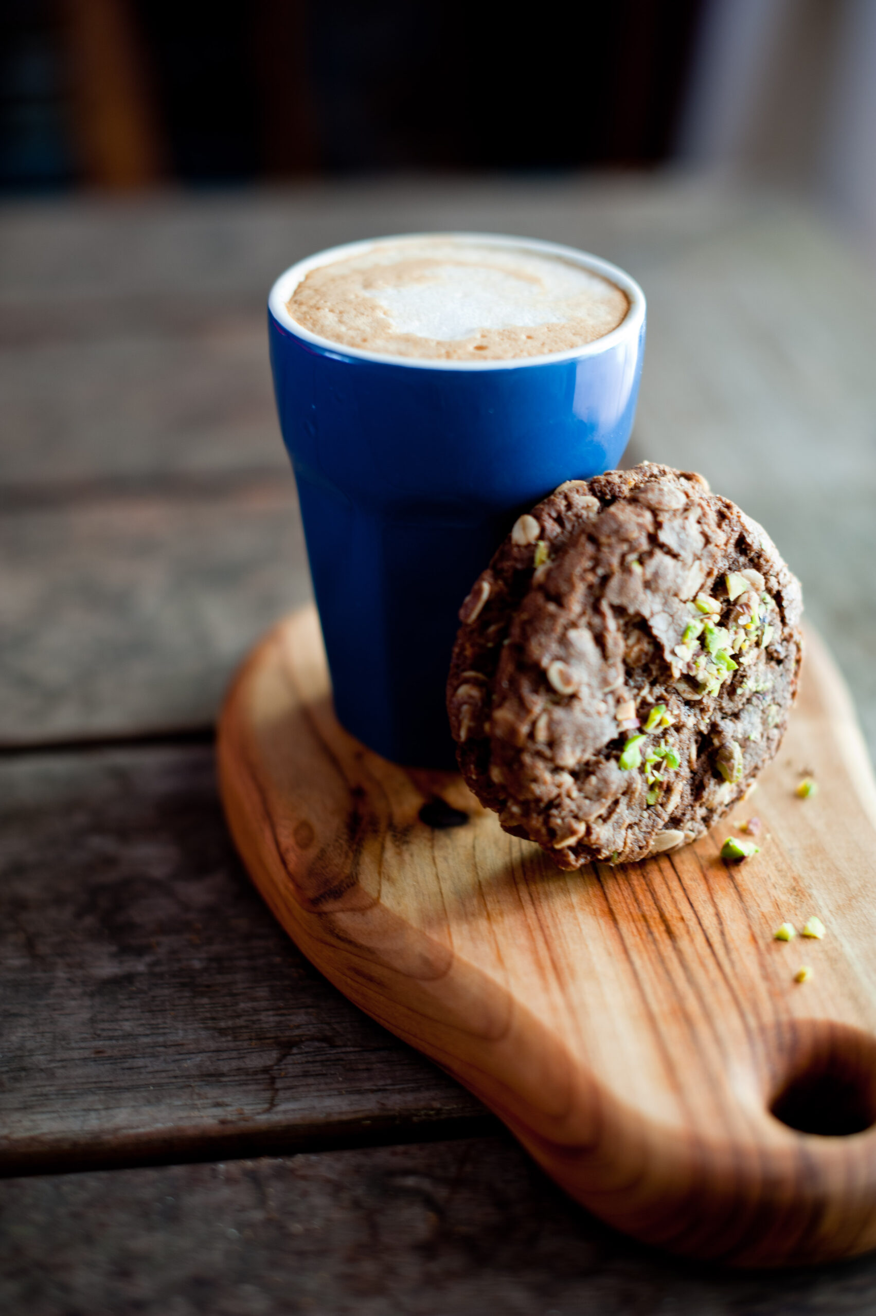pistachio sprinkled chocolate daate Anzac biscuits leaning on a coffee