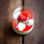 Wine glass filled with Pannacotta, tuile, marshmallow, strawberry anise syrup.