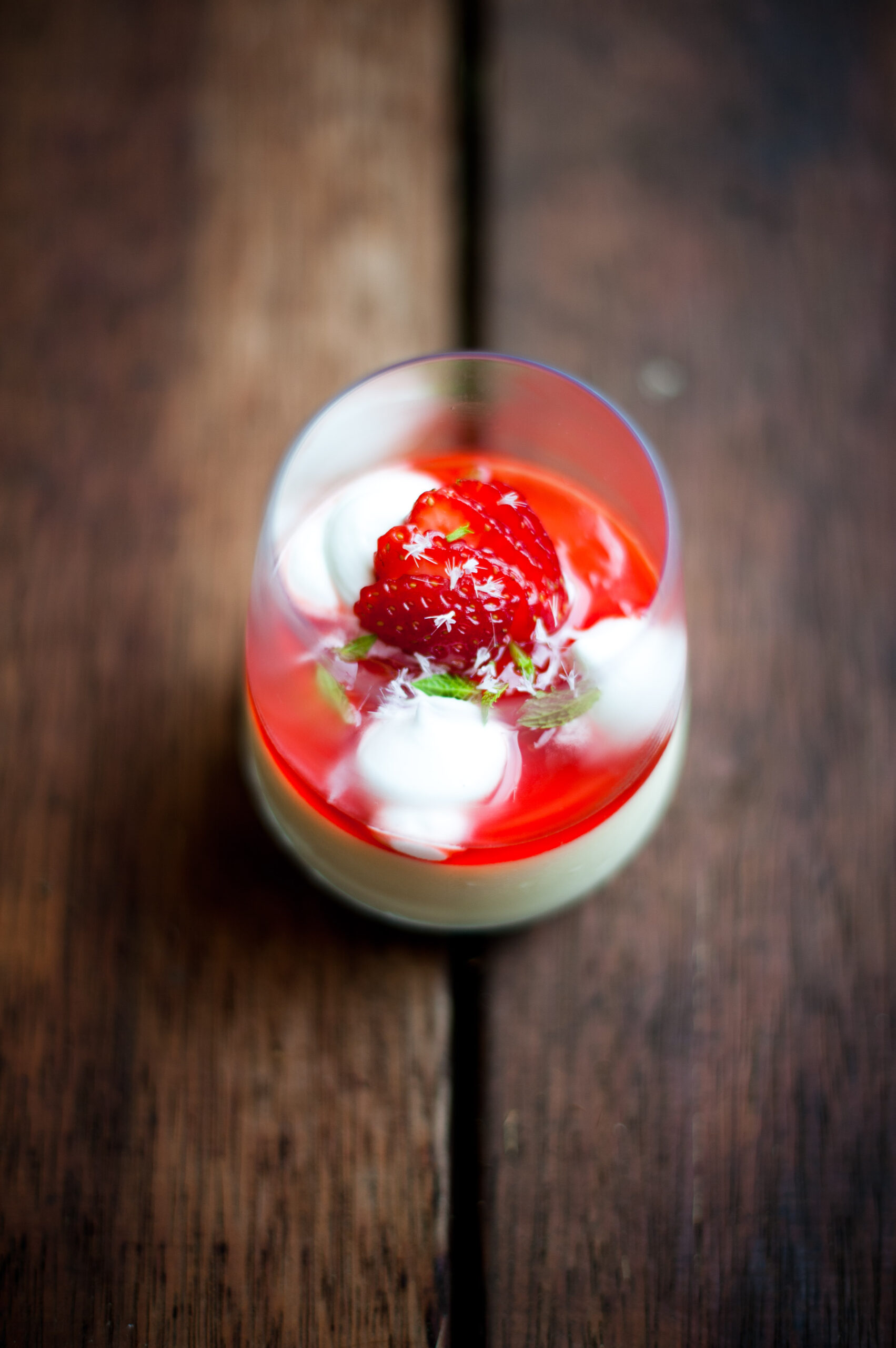 Wine glass filled with Pannacotta, tuile, marshmallow, strawberry anise syrup.