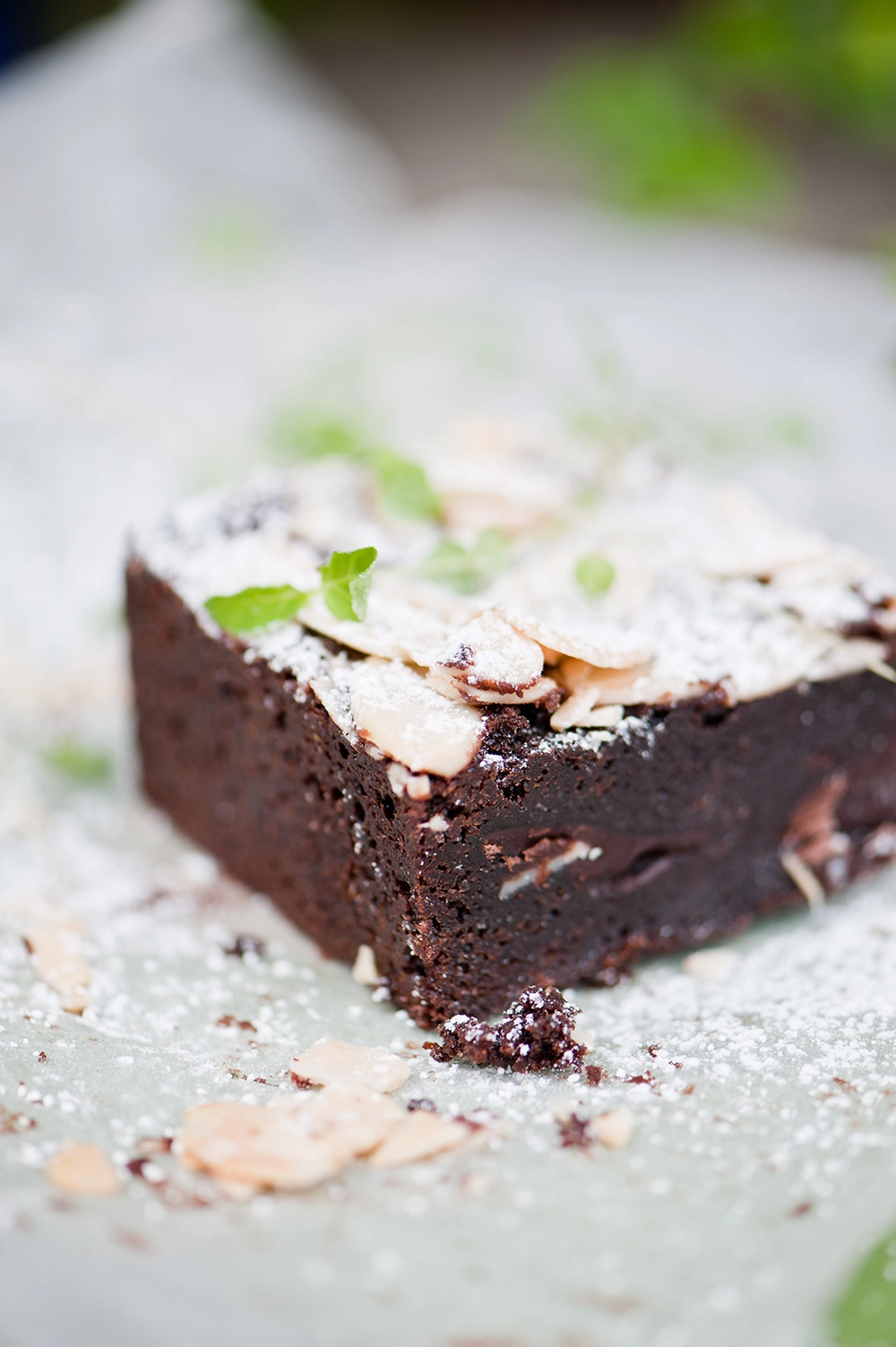 gluten free chococlate brownie dusted with icing sugar and flaked almond