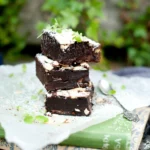 Stack of rich chocolate brownies dusted with icing sugar
