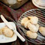 Sweet little Chai Madeleines on a cooling rack dusted with icing sugar - gluten free