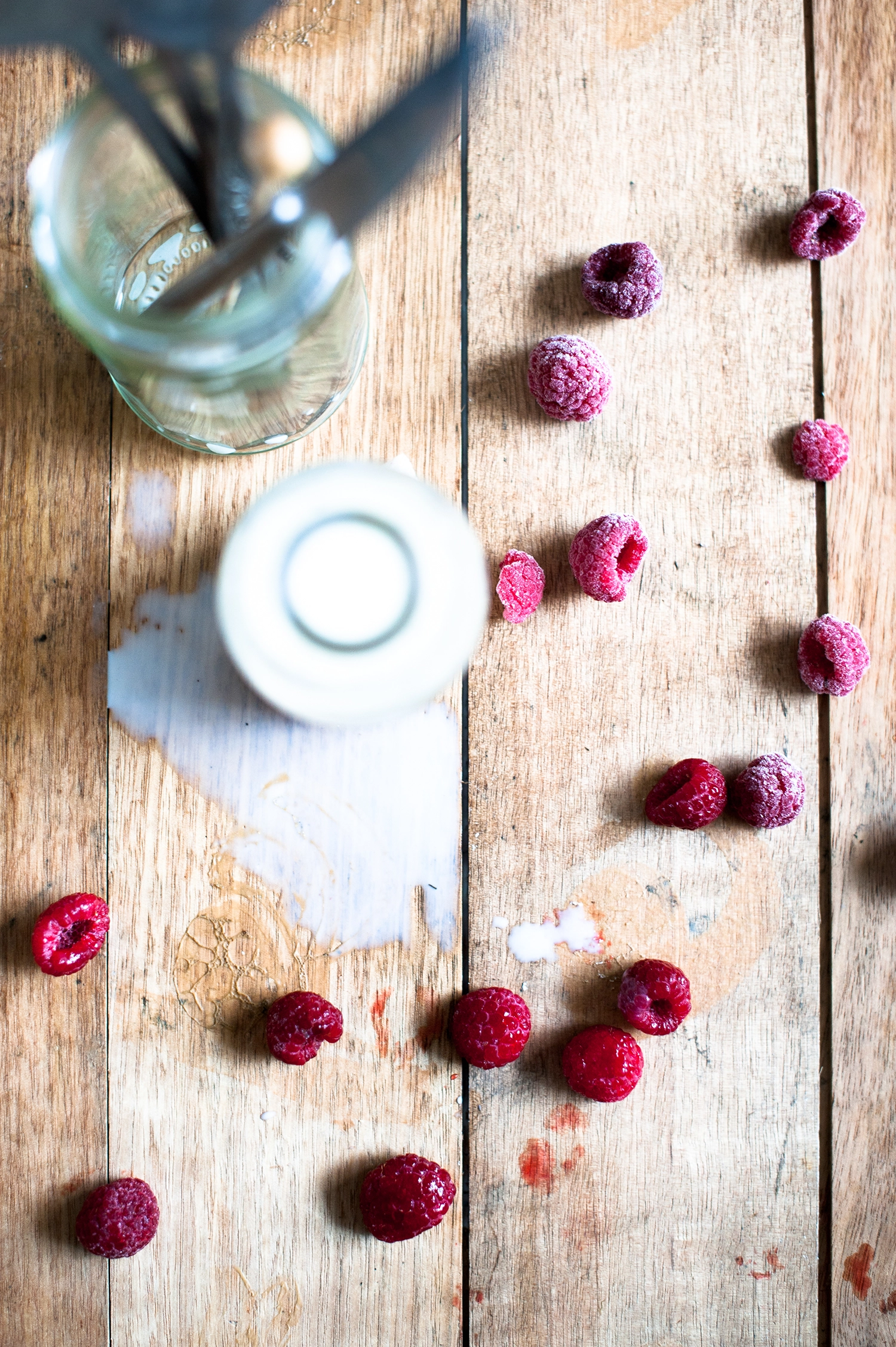 milk bottle with spilt milk and scattered raspberries